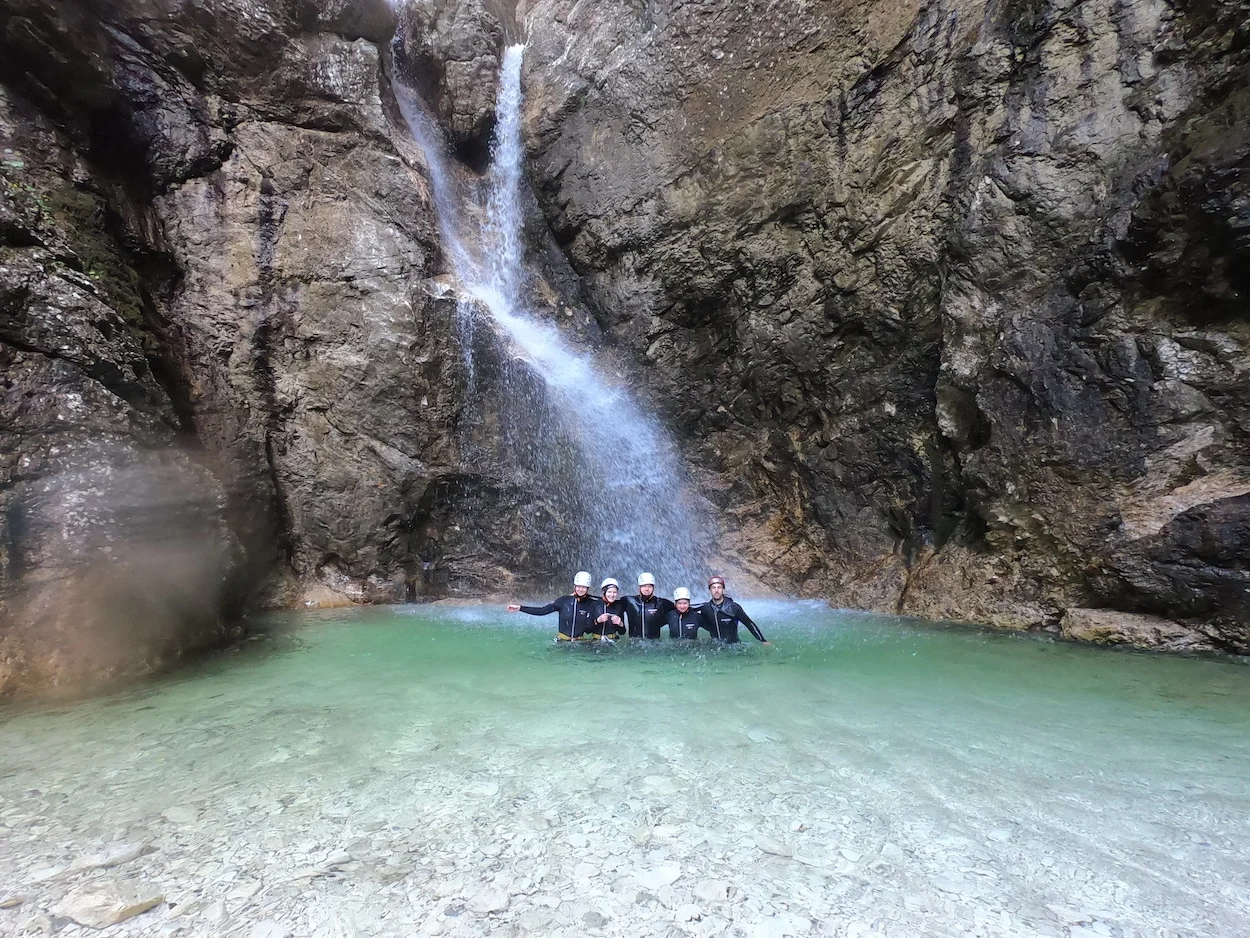 Photo de groupe en canyoning sous une chute d'eau